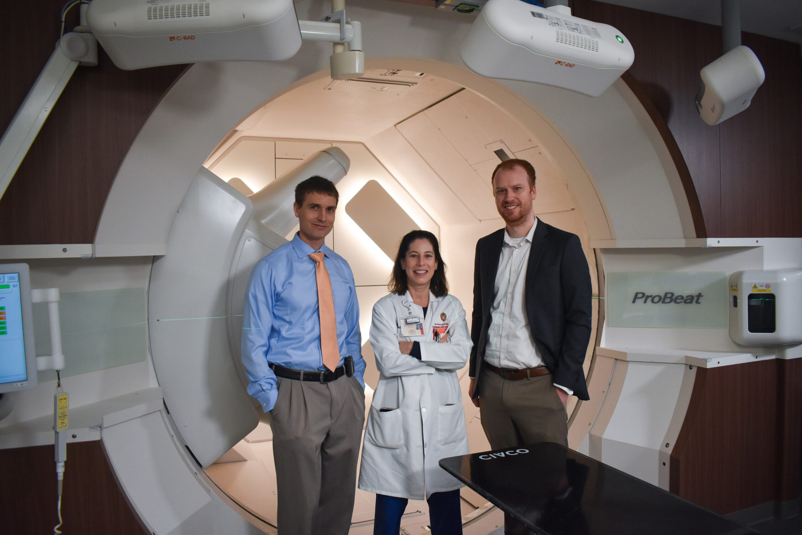 Three doctors stand in front of new gantry room technology