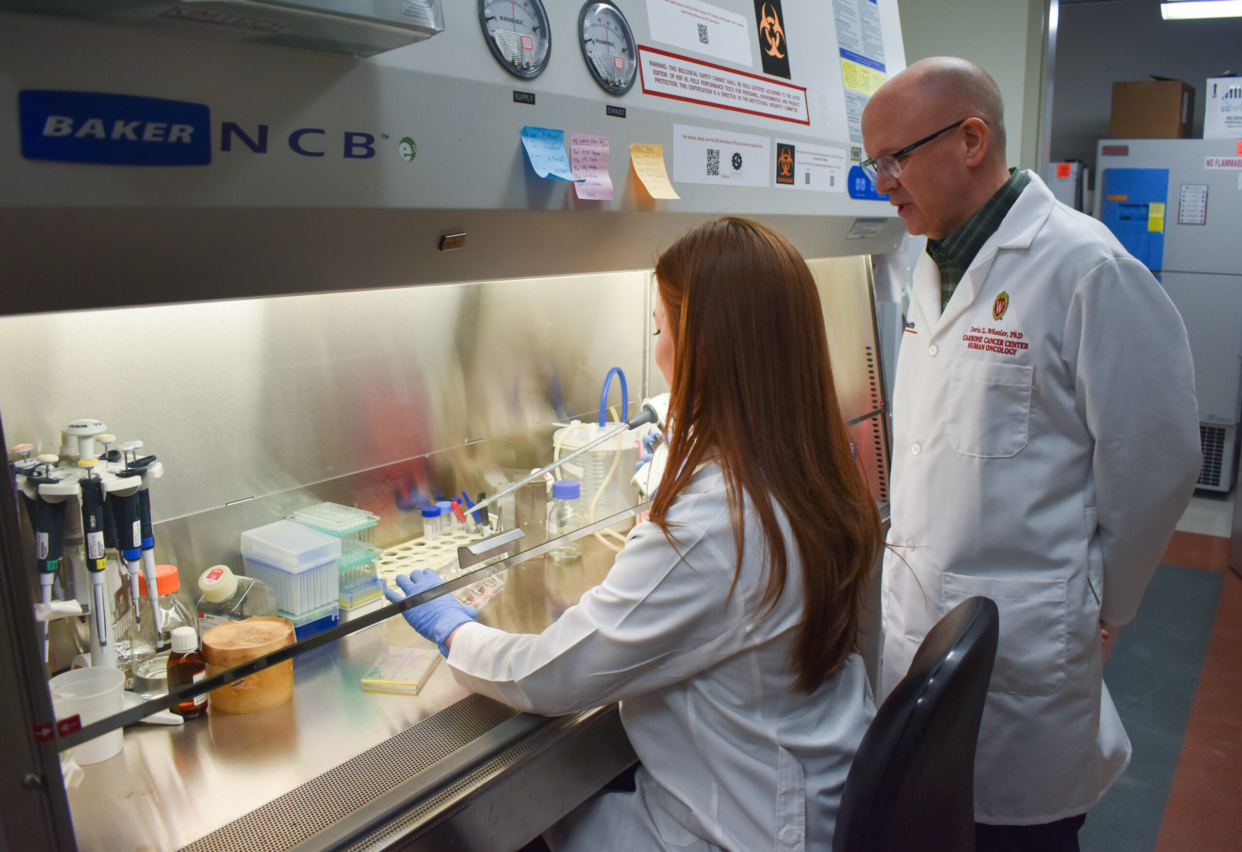 Deric Wheeler and lab member with pipette and hood
