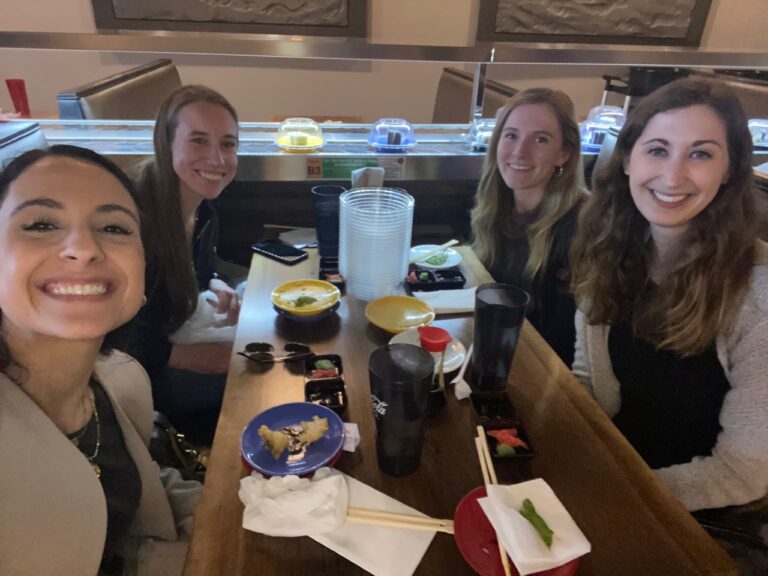 Four female residents sit at a table and smile