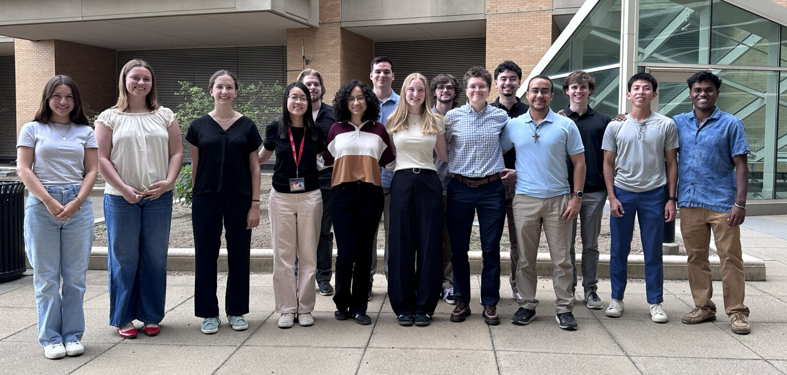 Large group of college students stand outside in front of building